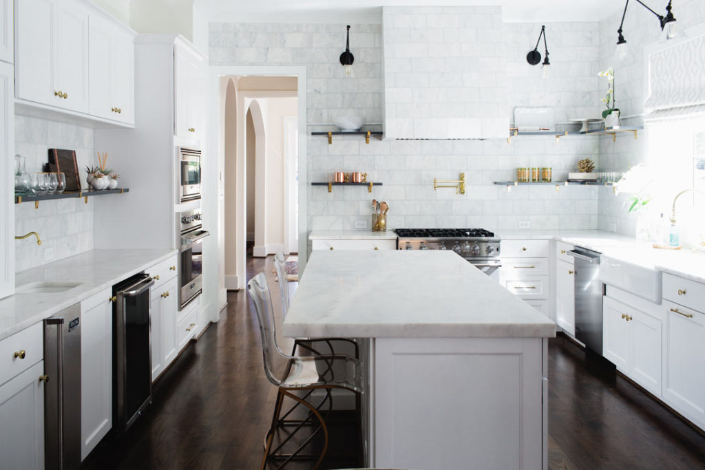 A designer kitchen with classic white kitchen cabinets with clean Alba Vera marble countertops.