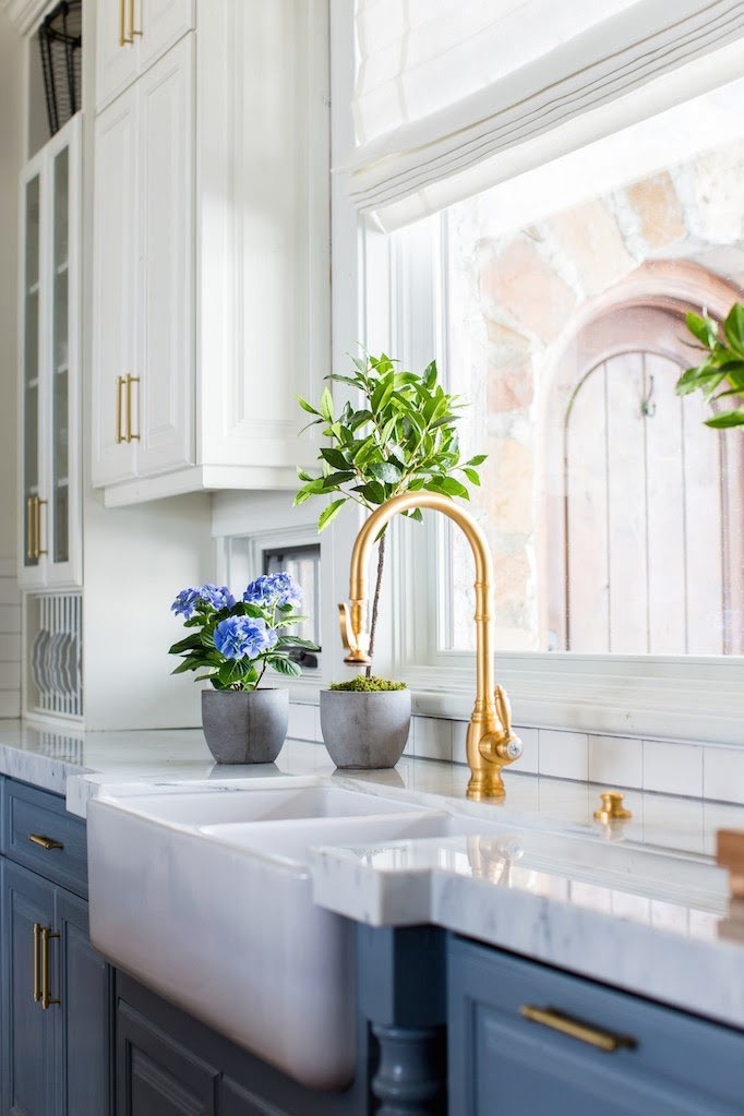 Brass Waterstone faucet in a brightly lit kitchen.
